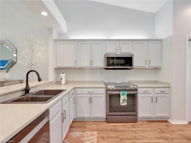 Kitchen featuring stainless steel appliances, light countertops, white cabinets, light wood-style flooring, and recessed lighting