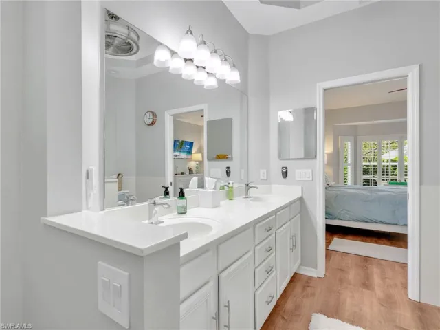 Full bath featuring connected bathroom, double vanity, and light wood-style flooring