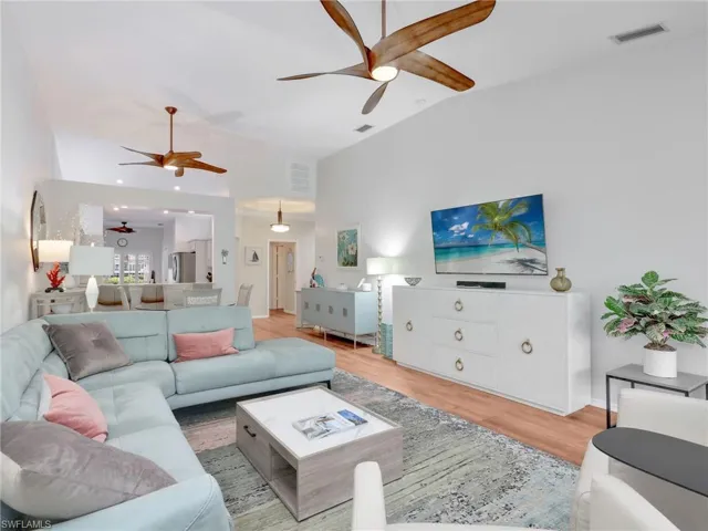 Living room with wood finished floors, ceiling fan, and vaulted ceiling