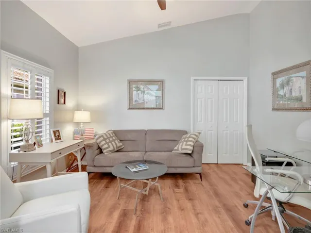 Living room with lofted ceiling, wood finished floors, an office area, and a ceiling fan