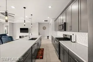 Kitchen featuring stainless steel appliances, pendant lighting, ceiling fan, open floor plan, and light tile patterned floors