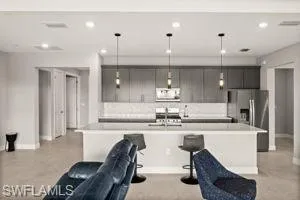 Kitchen with light countertops, an island with sink, a kitchen bar, open floor plan, and recessed lighting