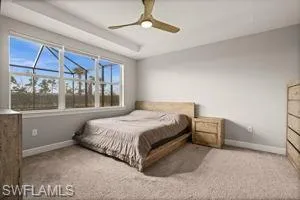 Bedroom with carpet flooring, ceiling fan, a raised ceiling, and a sunroom