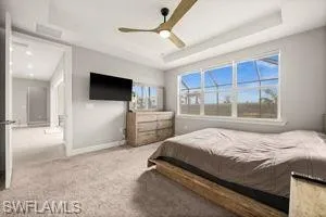 Carpeted bedroom with a raised ceiling and a ceiling fan