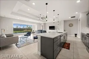 Kitchen with open floor plan, recessed lighting, hanging light fixtures, light countertops, and an island with sink