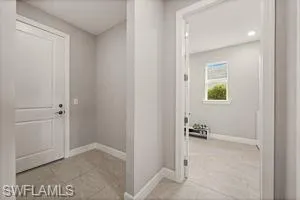 Hall featuring baseboards and light tile patterned flooring