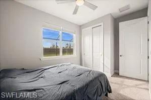 Carpeted bedroom featuring ceiling fan and a closet