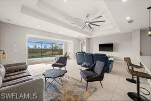 Tiled living room with a raised ceiling, ceiling fan, and recessed lighting