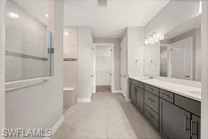 Bathroom with double vanity, a walk in shower, light tile patterned floors, and a walk in closet