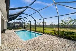 Outdoor pool with a sunroom, glass enclosure, and a patio