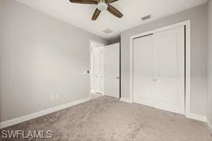 Unfurnished bedroom featuring light colored carpet, a closet, and ceiling fan
