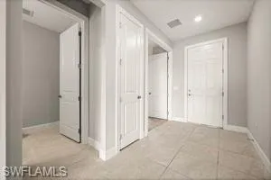 Corridor with light tile patterned flooring and recessed lighting