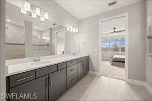 Ensuite bathroom featuring double vanity, light tile patterned flooring, and a shower