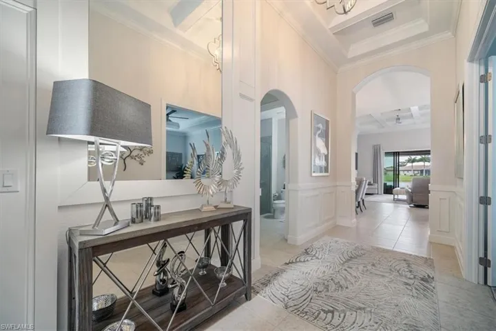 Corridor featuring beamed ceiling, ornamental molding, coffered ceiling, and light tile floors