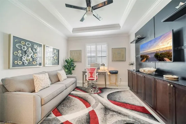 Living room with crown molding, carpet, ceiling fan, and a raised ceiling