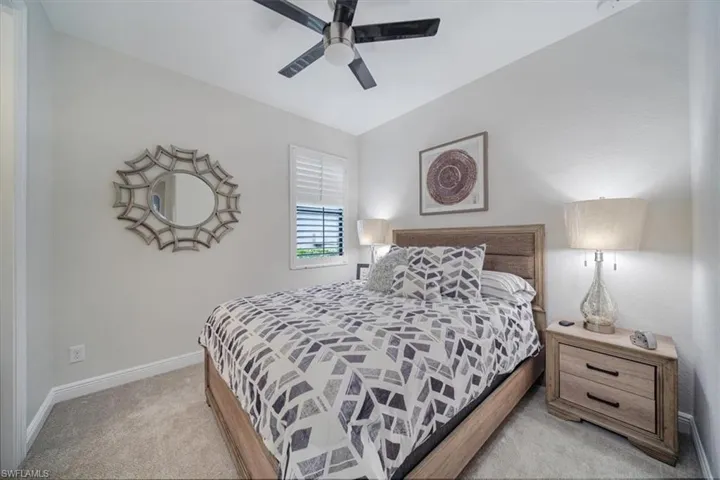 Carpeted bedroom with ceiling fan and vaulted ceiling