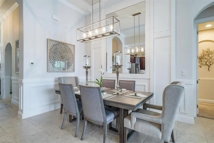 Tiled dining room with ornamental molding and a chandelier