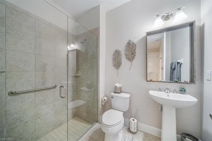 Bathroom featuring a shower with shower door, toilet, and tile floors