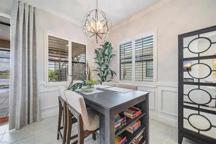 Tiled dining room featuring an inviting chandelier and crown molding