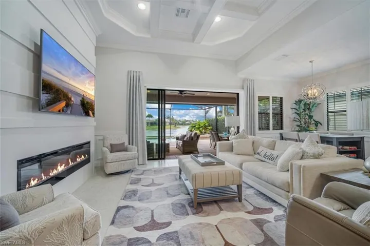 Living room featuring crown molding, beam ceiling, a chandelier, coffered ceiling, and light tile flooring