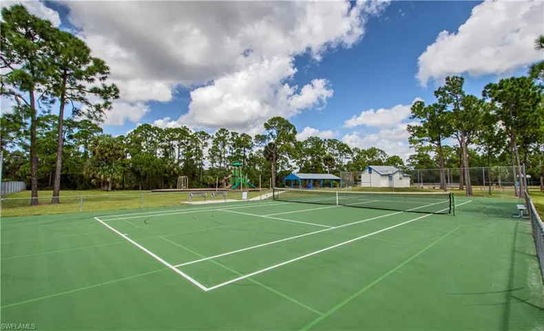 View of tennis court with community basketball court and view of wooded area