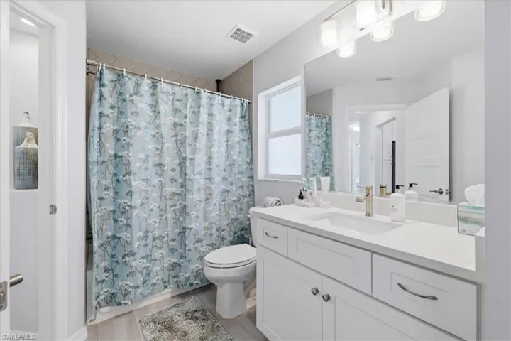 Bathroom featuring vanity, a shower with shower curtain, and light wood-style flooring