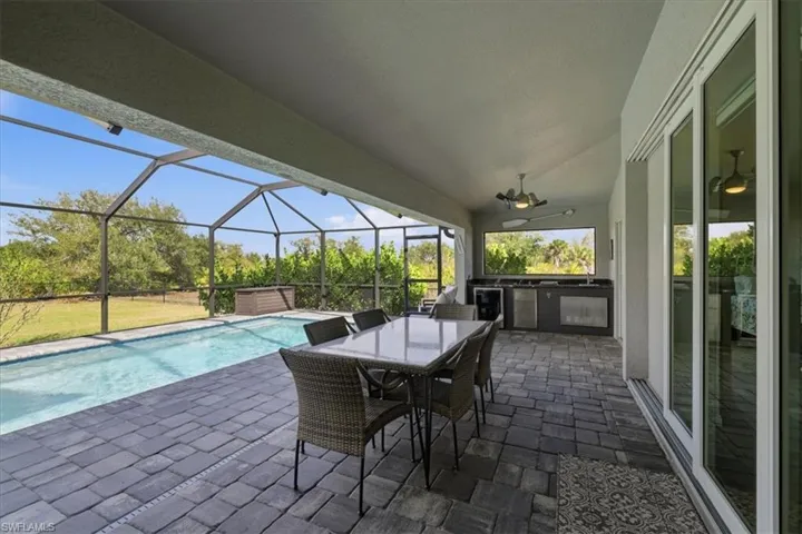 View of patio featuring an outdoor kitchen / dining area, a sunroom, cage, ceiling fan, and an outdoor pool
