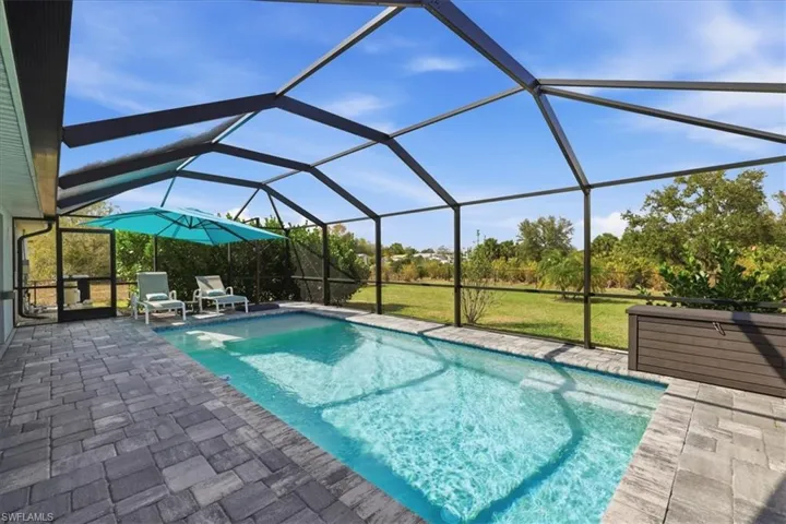 Swimming pool featuring a sunroom, cage, a lawn, and a patio area