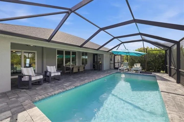 Swimming pool with outdoor dining area, a sunroom, and cage