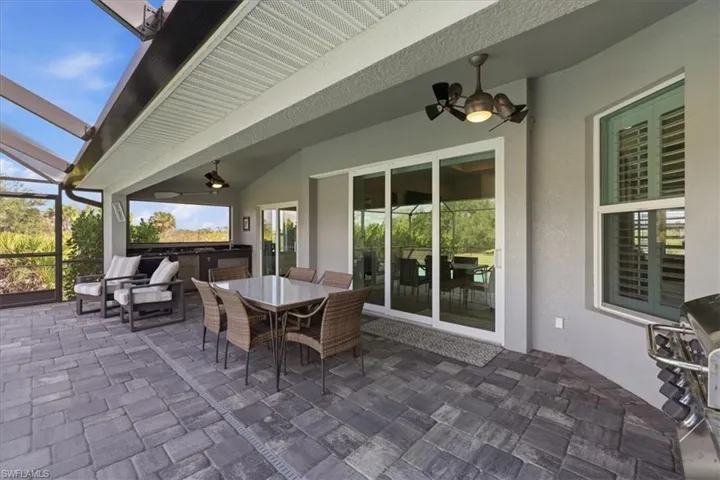 View of patio / terrace with ceiling fan, a sunroom, a lanai, and an outdoor kitchen / dining area