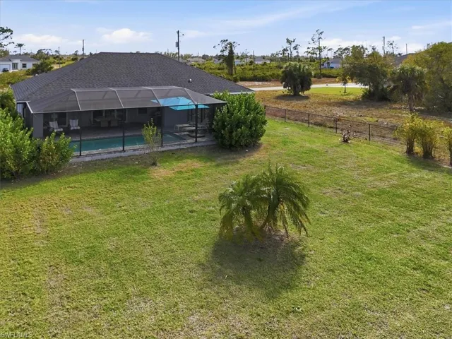 Fenced backyard with an outdoor pool, glass enclosure, a sunroom, and a patio