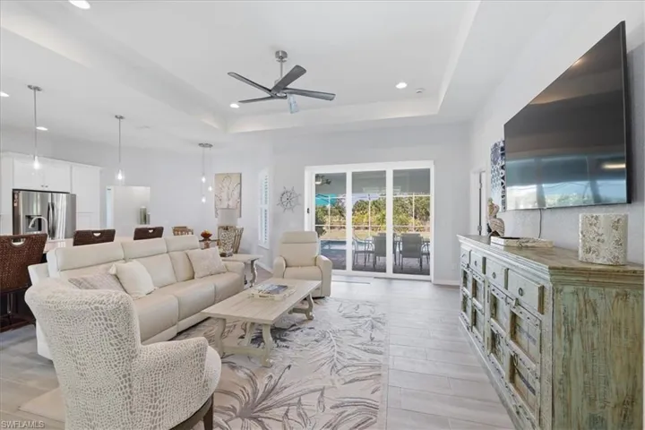 Living area with ceiling fan, wood finish floors, recessed lighting, and a tray ceiling