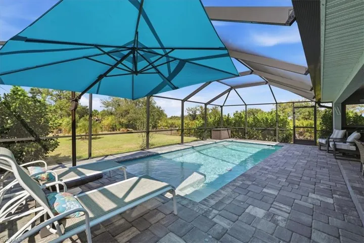 Outdoor pool featuring a sunroom, a lanai, a patio, and a lawn