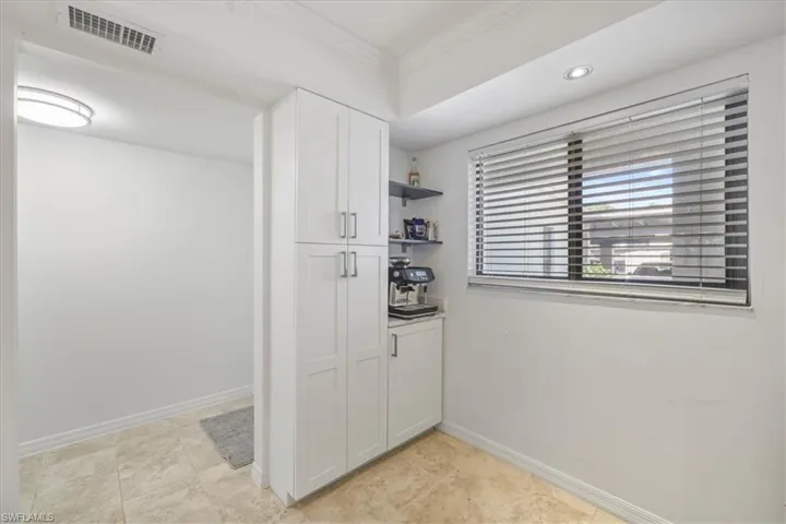 Kitchen featuring open shelves, white cabinets, and crown molding