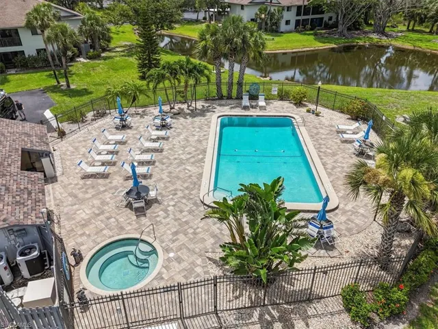 Community pool featuring a water view, a patio area, and a fenced backyard