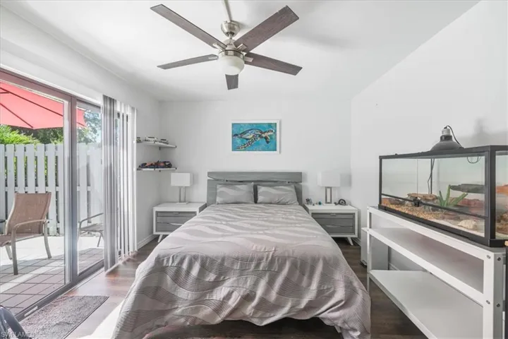 Bedroom with dark wood-style floors, access to outside, and ceiling fan