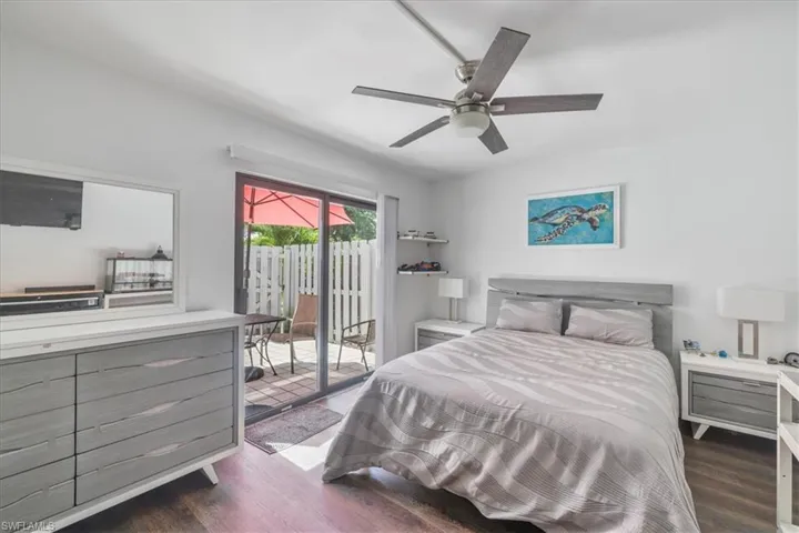 Bedroom with dark wood finished floors, ceiling fan, and access to outside