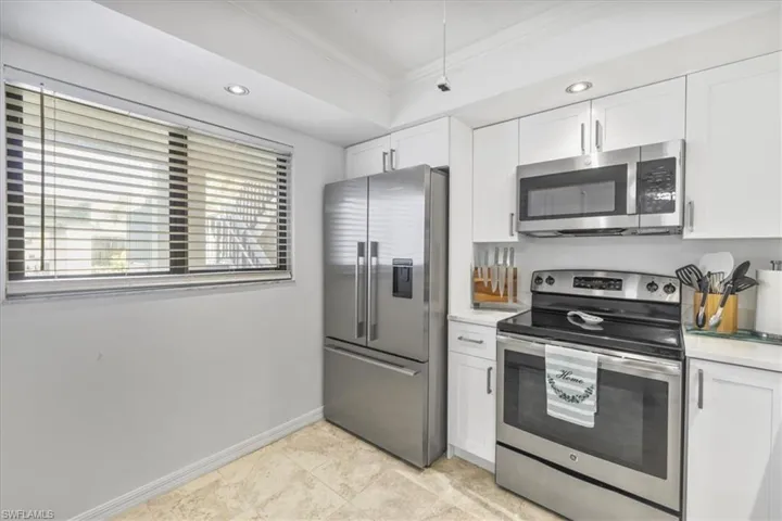 Kitchen with appliances with stainless steel finishes, white cabinetry, crown molding, and recessed lighting