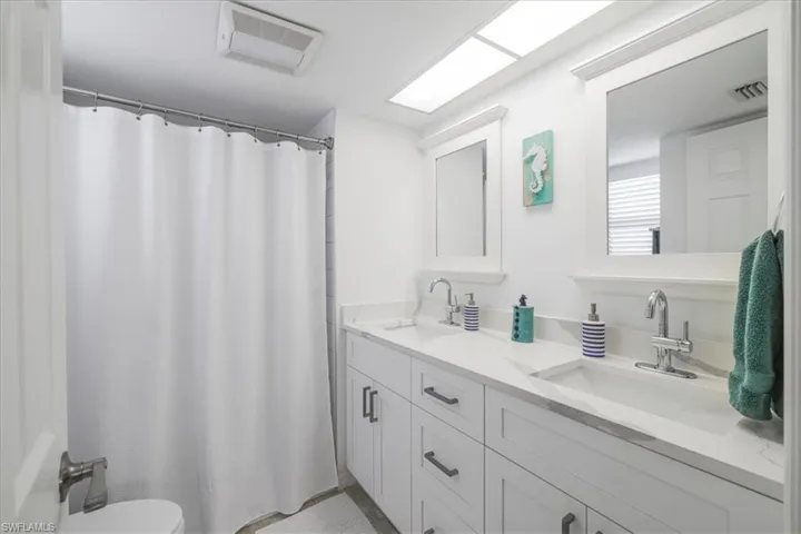 Full bath with a shower with curtain and double vanity