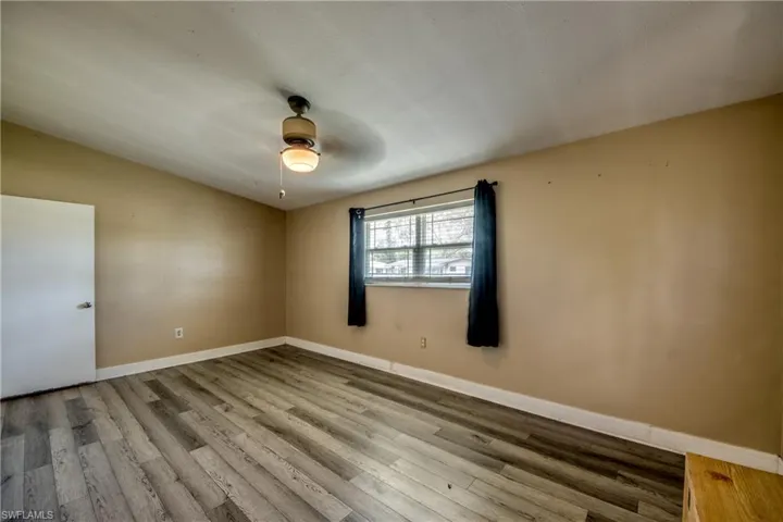 Unfurnished room with wood finished floors, a ceiling fan, and vaulted ceiling