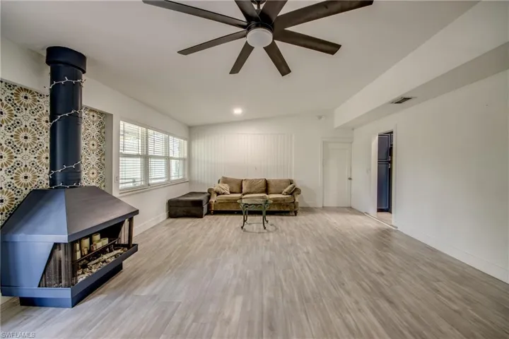 Living room featuring a ceiling fan, wood finished floors, and a wood stove
