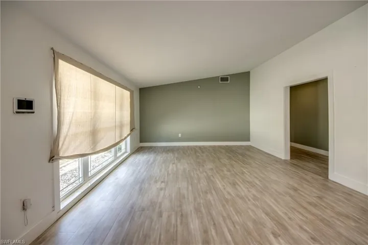 Spare room with wood finished floors and lofted ceiling