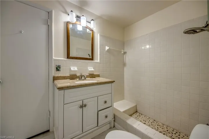 Full bath with tiled shower, vanity, and tile walls