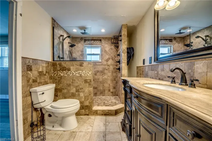 Full bathroom with tile walls, vanity, and a walk in shower