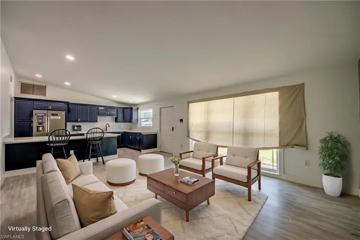 Living area with light wood-style flooring, recessed lighting, and vaulted ceiling