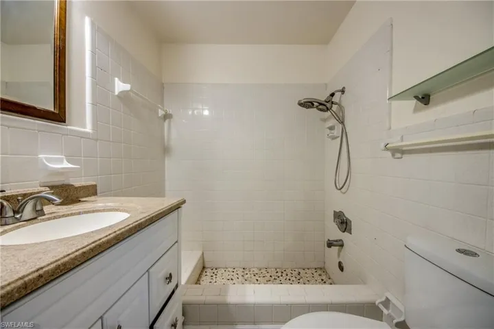 Full bath with tile walls, a tile shower, and vanity