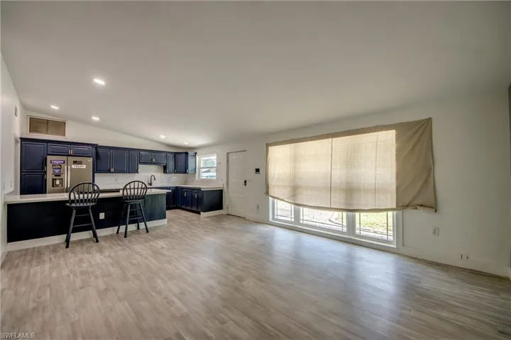 Living area with light wood-type flooring, recessed lighting, and vaulted ceiling