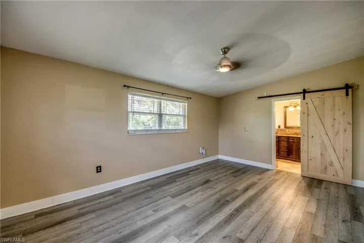 Spare room featuring a barn door, wood finished floors, and a ceiling fan