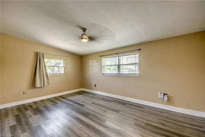 Spare room featuring wood finished floors, a ceiling fan, and lofted ceiling