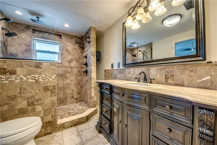 Bathroom featuring tile walls, a walk in shower, and vanity